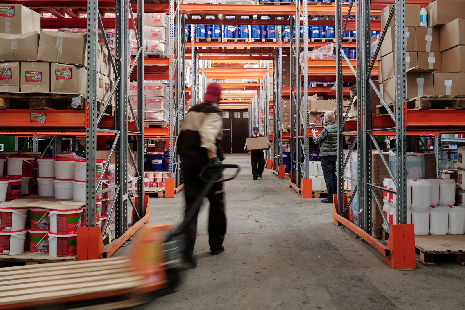 Depósito de distribuidora con estanterías altas y operarios moviendo mercadería
