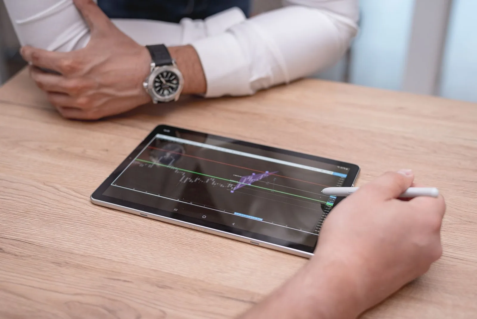Manos usando una tablet con lápiz sobre un escritorio de trabajo