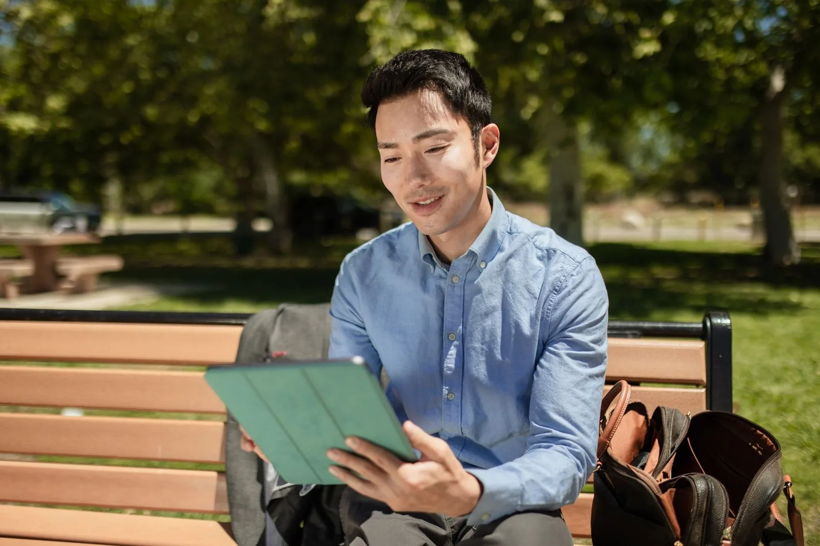 Hombre usando una tablet en un banco de plaza al aire libre, sin depender del Wi-Fi